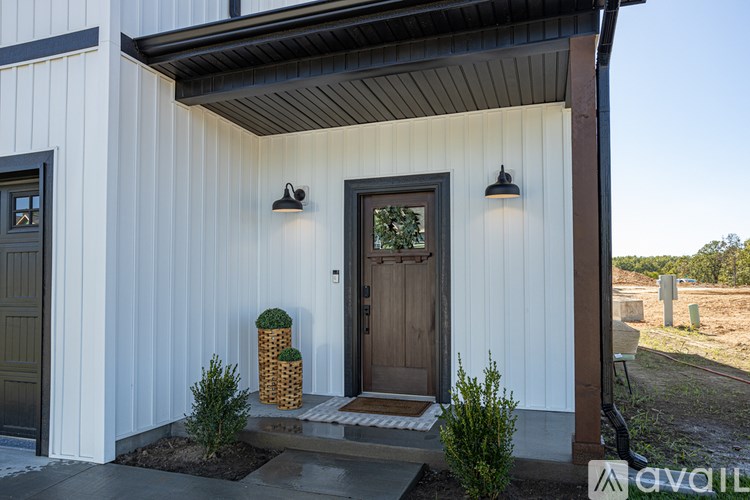 A white house with a brown door and a small garden in front.