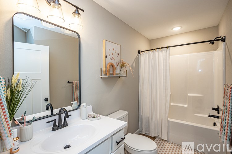 A bathroom with a white sink, toilet, and shower curtain.