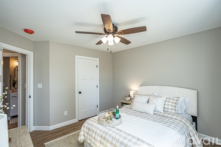 A bedroom with a bed, a ceiling fan, and a nightstand.