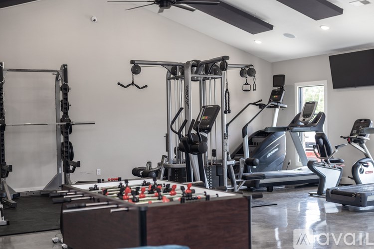 A gym with a variety of equipment including treadmills, weights, and a foosball table.