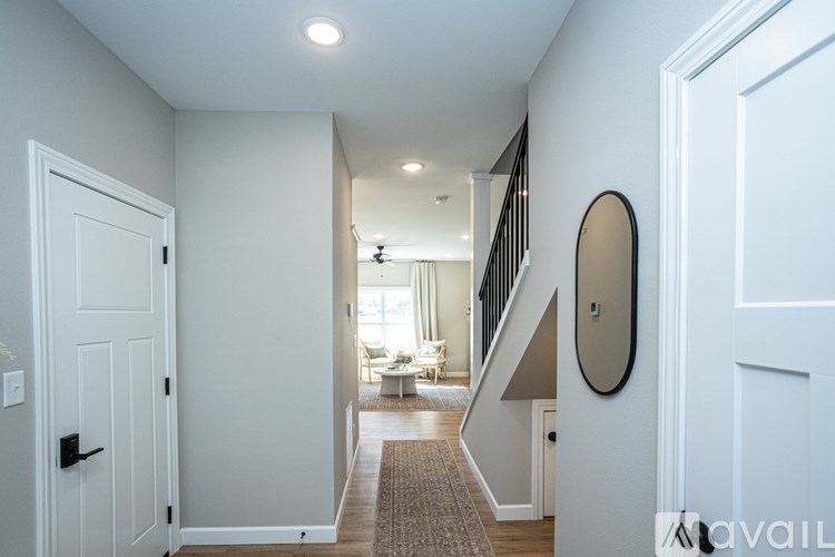 A hallway with a white door and a round mirror on the wall.
