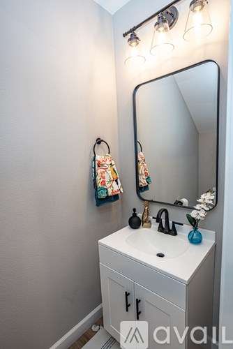 A bathroom sink with a mirror above it and a towel hanging on the wall.