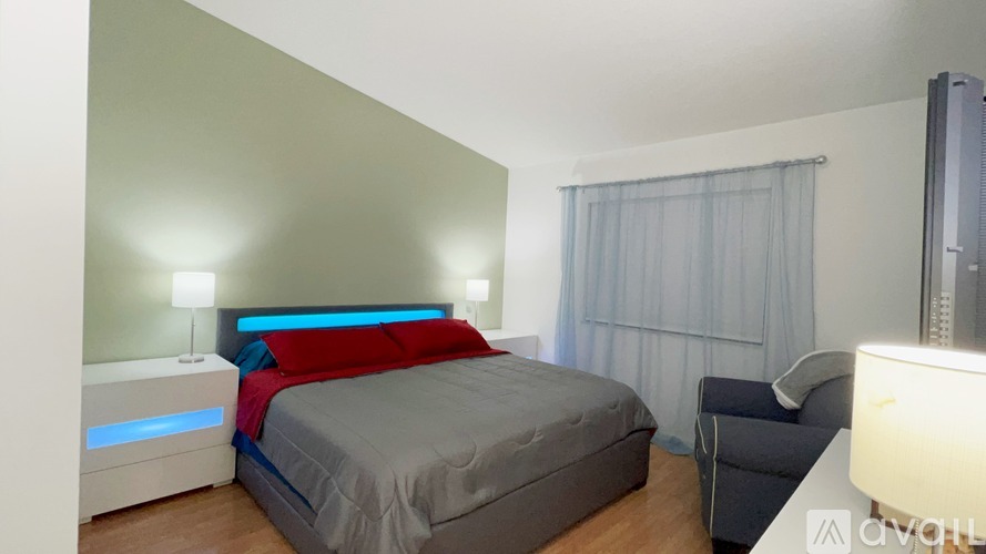 A bedroom with a bed, a chair, and a mirror.
