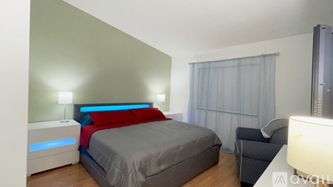 A bedroom with a bed, a chair, and a mirror.