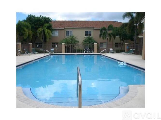 A swimming pool in front of a building with palm trees.
