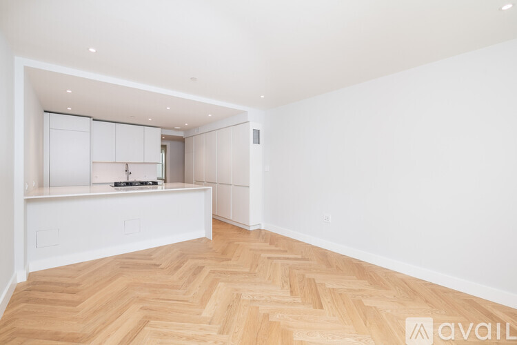 A spacious room with wooden flooring and white walls.