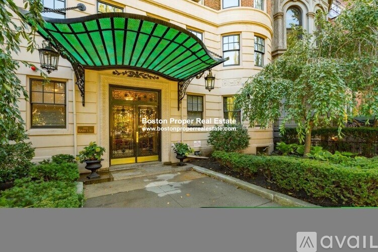 A building entrance with a green awning and a sign for Boston Proper Real Estate.