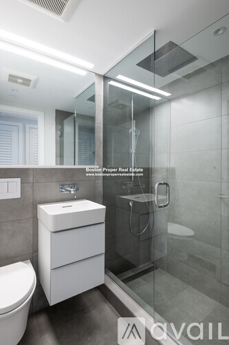 A modern bathroom with a toilet, sink, and glass shower stall.