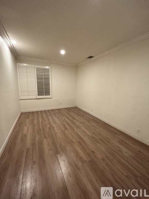 A room with wooden flooring and a window with blinds.
