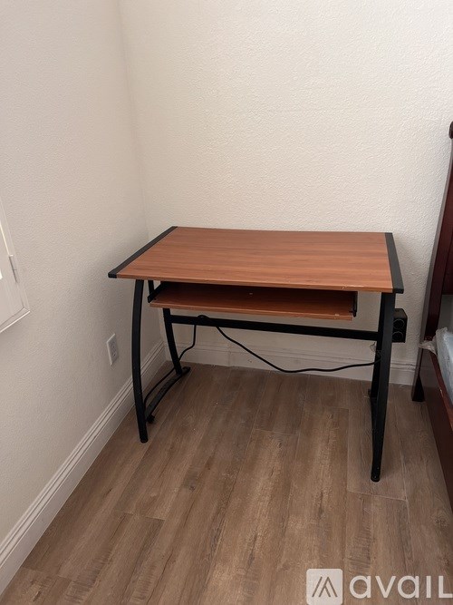 A wooden table with black legs sits in a room with light colored walls.