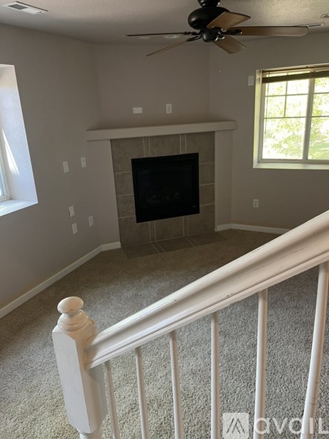 A living room with a fireplace and a ceiling fan.