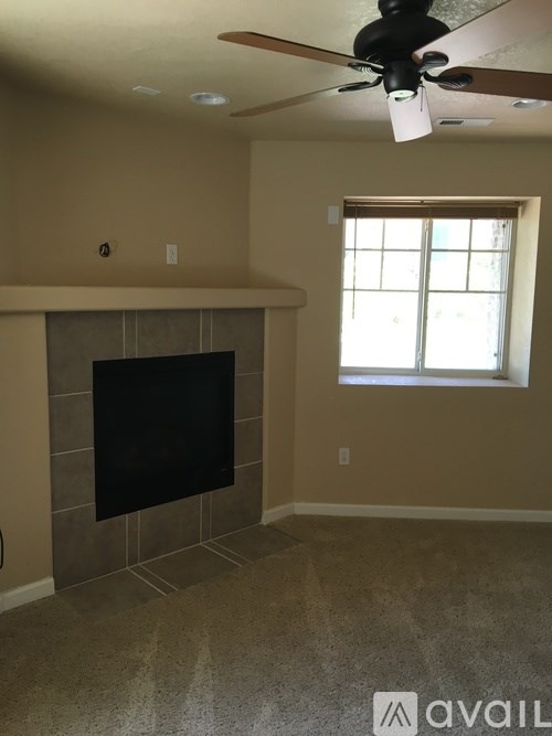 A living room with a fireplace and a ceiling fan.