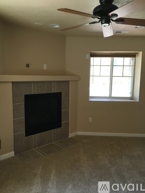 A living room with a fireplace and a ceiling fan.