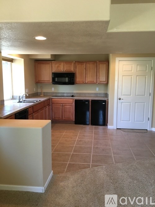 A kitchen with brown cabinets and a black microwave.