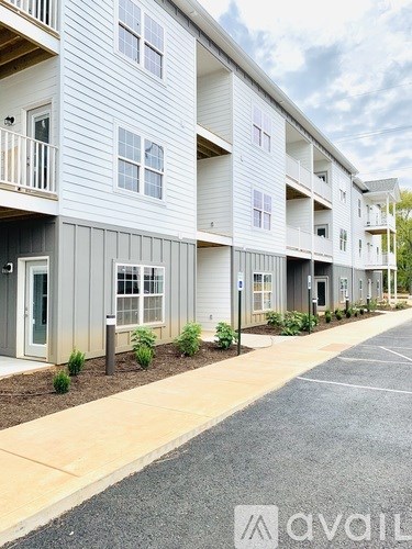 A row of modern apartment buildings with balconies and small front yards.