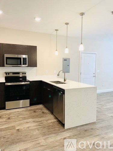 A modern kitchen with a white countertop and dark wood cabinets.