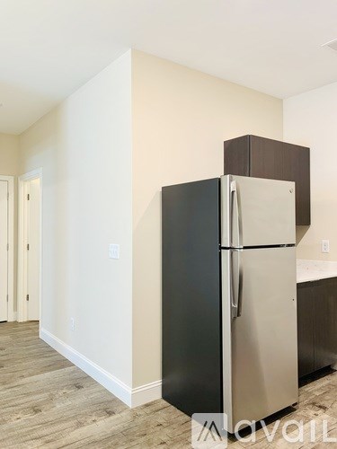 A black fridge in a room with wooden flooring.
