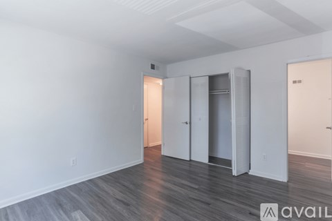 A room with a white wall and a wooden floor with three doors.