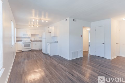 A spacious kitchen with white cabinets and a wooden floor.