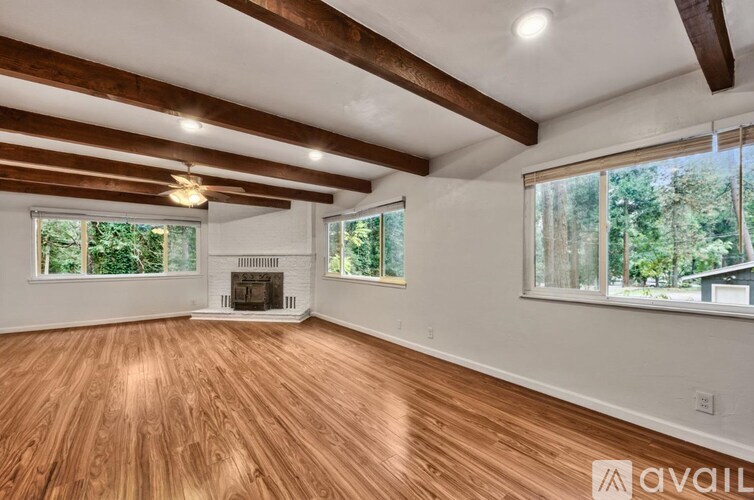 A spacious room with wooden floors and a fireplace.