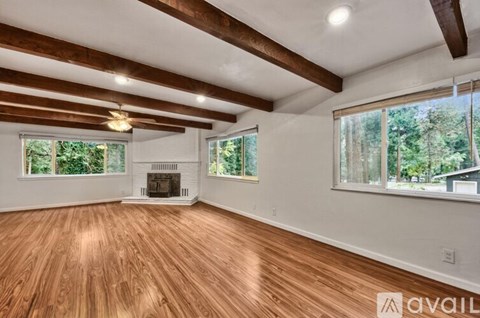 A spacious room with wooden floors and a fireplace.