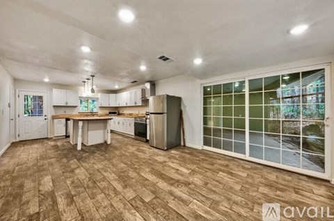 A kitchen with a wooden floor and white cabinets.