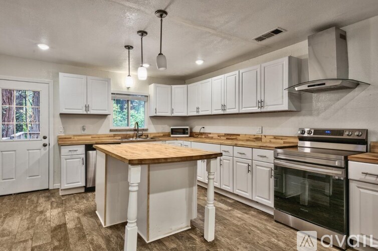 A kitchen with white cabinets and a wooden island.