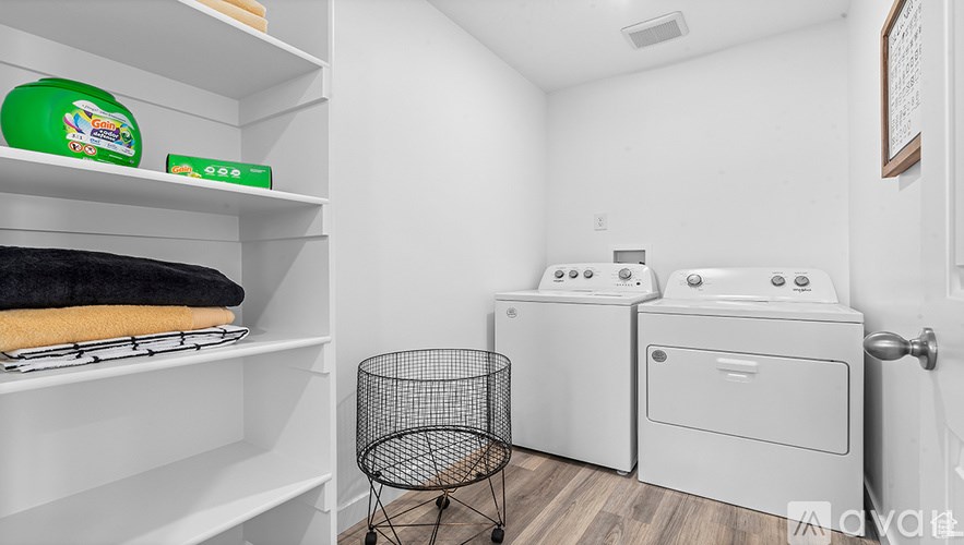 A laundry room with a washer and dryer and a basket.