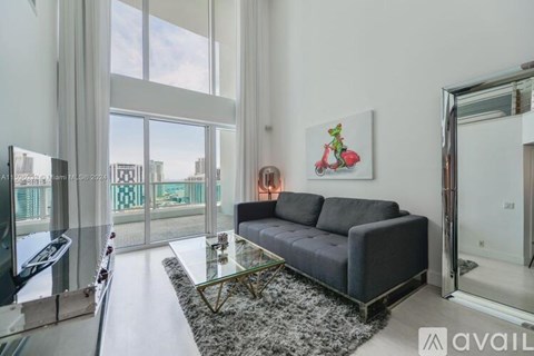 A living room with a grey couch and a red scooter painting on the wall.