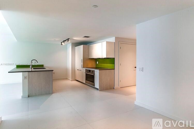 A kitchen with a white floor and white walls with a green counter top.