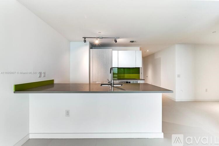 A modern kitchen with a white island and green accent.