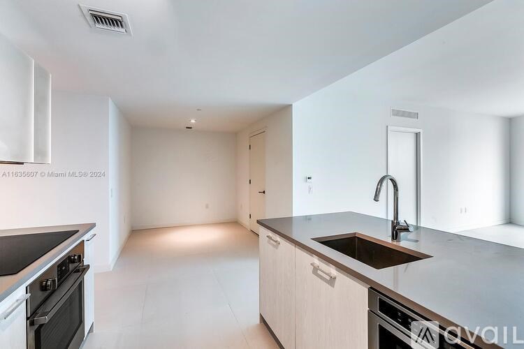 A modern kitchen with a stove top oven and a sink.