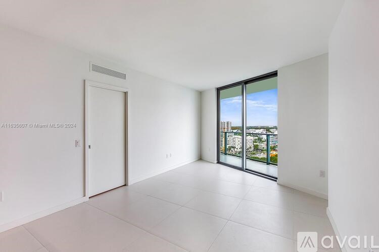 A white room with a sliding glass door leading to a balcony.