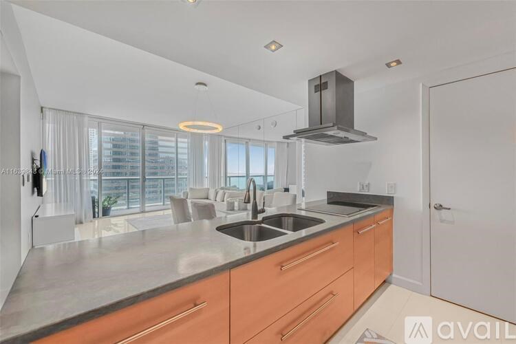 A modern kitchen with a stainless steel sink and orange cabinets.