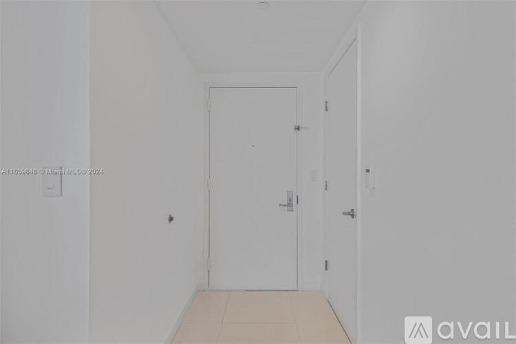 A white door is in the middle of a white hallway.