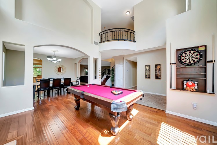 A pool table in a room with a dartboard on the wall.