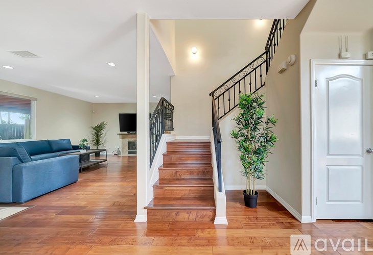 A living room with a blue couch and a staircase with a black railing.