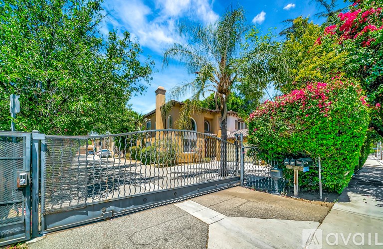 A gated entrance to a property with a brick house and greenery.