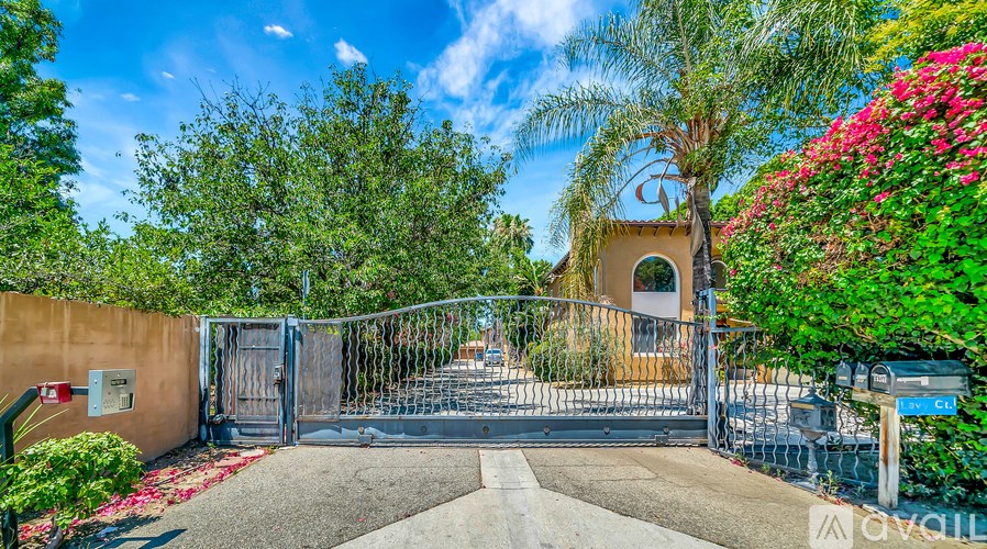 A gated entrance to a property with a small building and a tree in the background.