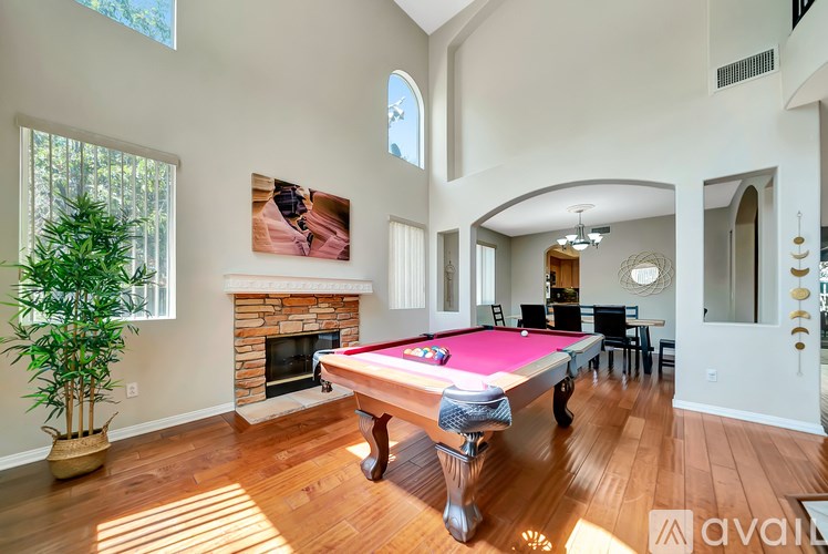 A pool table in a room with a fireplace and a potted plant.