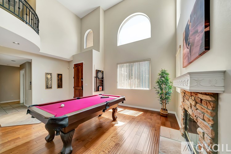 A pool table in a room with a fireplace and a plant.