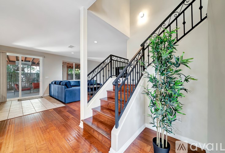 A living room with a blue couch and a staircase with a black railing.