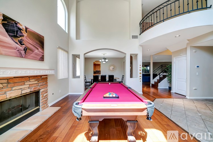 A pool table in a room with a fireplace and a painting on the wall.