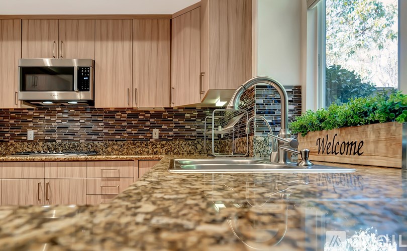 A kitchen with a stone backsplash and wooden cabinets.