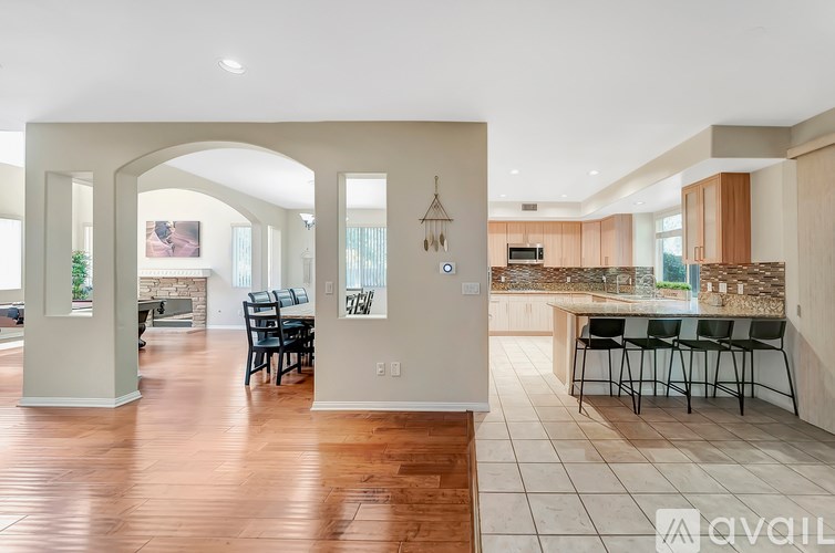 A spacious kitchen and dining area with a wooden floor and white walls.