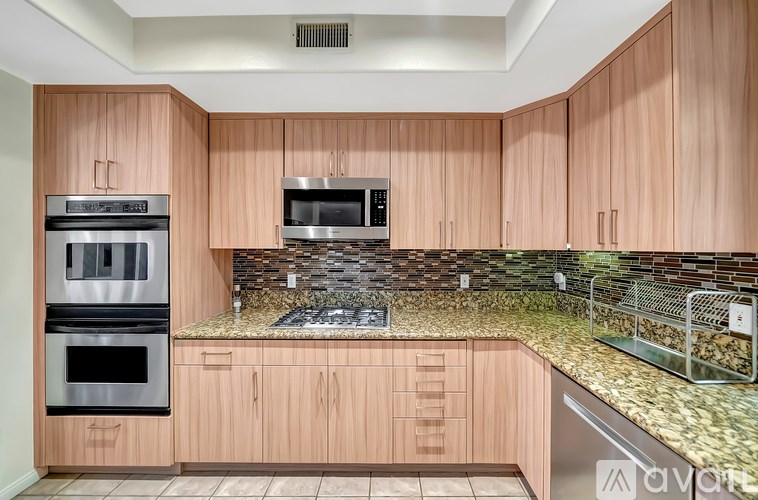 A kitchen with wooden cabinets and a stone backsplash.