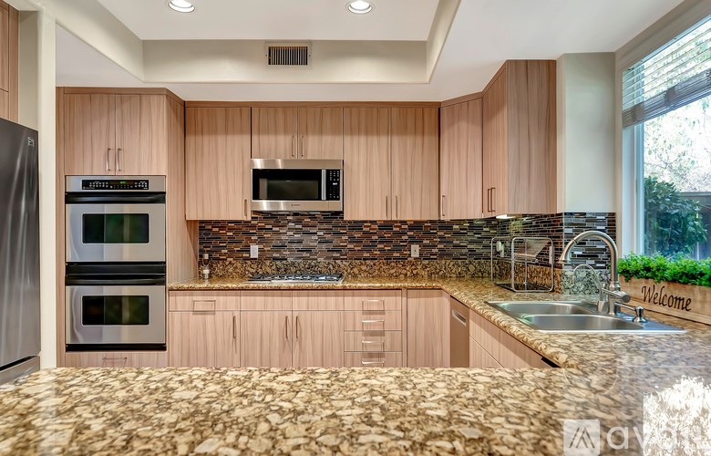 A kitchen with wooden cabinets and a stone backsplash.