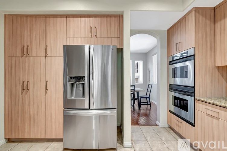 A kitchen with wooden cabinets and a stainless steel refrigerator.