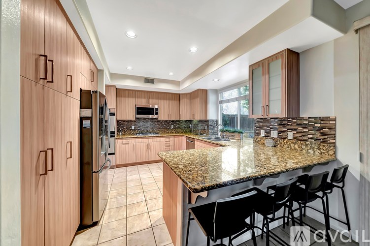A kitchen with a granite countertop and black barstools.