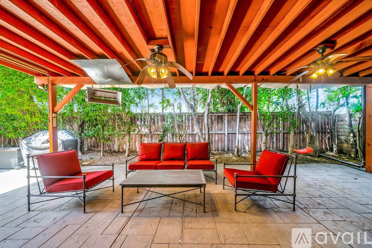 A patio with a wooden floor and red chairs.
